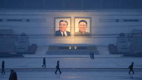 Pedestrians walk past portraits of late North Korean leaders Kim Il-sung and Kim Jong-il across Kim Il-sung square in Pyongyang on December 3, 2018. (Ed Jones/AFP)