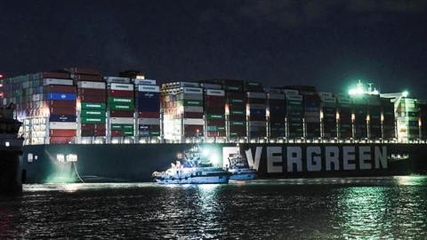 This picture taken late on March 27, 2021 shows a view of tugboats by the Panama-flagged MV 'Ever Given' (operated by Taiwan-based Evergreen Marine) container ship, which has been wedged diagonally across the span of the canal about six kilometres north o