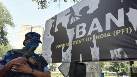 Rapid Action Force (RAF) personnel stand guard beside a banner installed by the supporters and activists of India's ruling Bharatiya Janata Party (BJP) during a protest demanding ban on Popular Front of India (Getty Images)