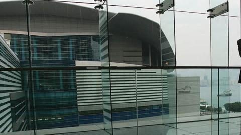 A delegate stands in front of a window at the Hong Kong Convention and Exhibition Centre during the World Trade Organization (WTO) ministerial conference on 16 December, 2005 in Hong Kong (Photo by MN Chan/Getty Images)