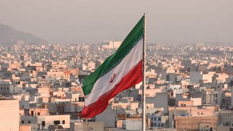 Iranian flag waving with city skyline on background in Tehran, Iran (Getty Images)