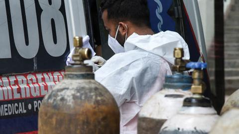 A health worker next to oxygen cylinders taking information from a COVID-19 coronavirus positive person, inside the ambulance, at MMC hospital in Guwahati, Assam, India on 25 May 2021. (David Talukdar/NurPhoto via Getty Images)