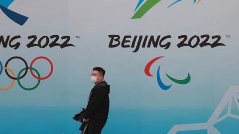 A Chinese man wears a protective mask as he walks in front the logos of the 2022 Beijing Winter Olympics at National Aquatics Centre on April 9, 2021 in Beijing, China. (Photo by Lintao Zhang/Getty Images)