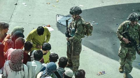 US soldiers stand guard as Afghan people wait at the Kabul airport in Kabul on August 16, 2021 (Photo by WAKIL KOHSAR/AFP via Getty Images)