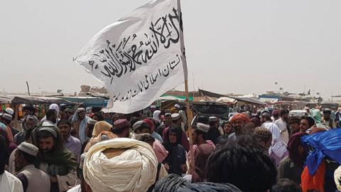 People gather around a Taliban flag as they wait for relatives released from jail in Afghanistan following an 'amnesty' by the Taliban, near the Pakistan-Afghanistan border crossing point in Chaman on August 17, 2021 (AFP via Getty Images)