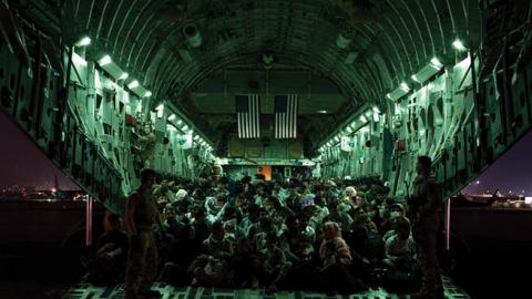 An air crew assists evacuees aboard a C-17 Globemaster III aircraft in support of the Afghanistan evacuation at Hamid Karzai International Airport on August 21, 2021 in Kabul, Afghanistan. (Taylor Crul/U.S. Air Force via Getty Images)
