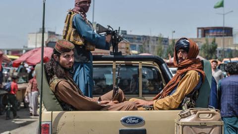 Taliban fighters on a pick-up truck move around a market area, flocked with local Afghan people at the Kote Sangi area of Kabul on August 17, 2021, after Taliban seized control of the capital following the collapse of the Afghan government (Photo by HOSHA