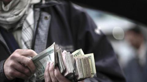 An Afghan street seller offers the local currency called 'afgani' in exchange for US dollars and few pre-paid mobile phone cards, in Kabul, on April 10, 2010. (MAURICIO LIMA/AFP VIA GETTY IMAGES)