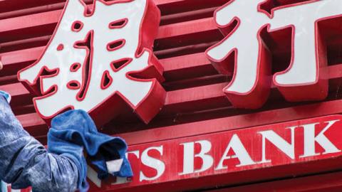 A worker cleans up the signage of a bank storefront on October 19, 2020 in Shanghai, China. (VCG/VCG via Getty Images)