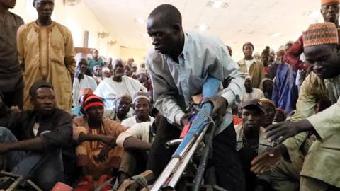 Members of the Yansakai vigilante group lay their weapons on the floor in Gusau, on December 3, 2019. (Photo by Kola Sulaimon / AFP via Getty Images)