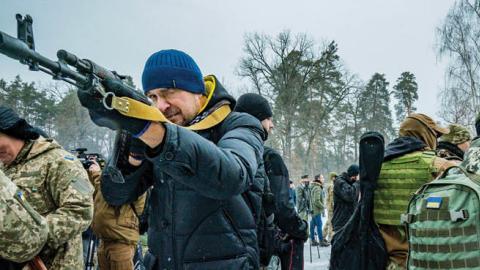 Civilian volunteer of the 112th Territorial Defense Brigade of Kiev points with his rifle during a military training for civilians in the outskirts of the city. (Photo by Celestino Arce/NurPhoto via Getty Images)