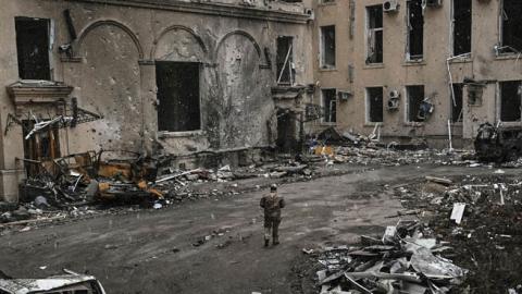 A Ukranian serviceman walks between rubble of the destroyed regional headquarters of Kharkiv on March 27, 2022. (Photo by Aris Messinis / AFP via Getty Images) 