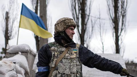 A territorial defense member signals to cars passing a checkpoint on April 3, 2022 in Kyiv, Ukraine. (Photo by Alexey Furman/Getty Images)