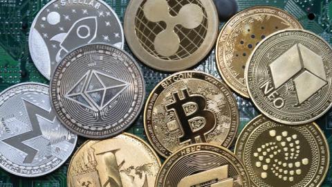 Metal coins imprinted with cryptocurrency logos placed on a computer board. (Ulrich Baumgarten/Getty Images)