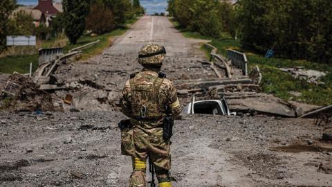 A soldier of the Kraken Ukrainian special forces unit observes the area at a destroyed bridge north of Kharkiv, on May 16, 2022. (Photo by Dimitar Dilkoff/ AFP)