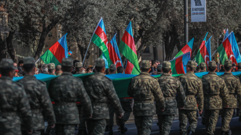 Azeri service members carry a giant flag during a procession marking the anniversary of the end of the 2020 military conflict over Nagorno-Karabakh breakaway region on November 8, 2021, in Baku, Azerbaijan. (Aziz Karimov/Getty Images)