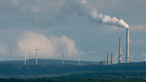 Turbines from the Mount Storm Wind Farm stand in the distance behind the Dominion Mount Storm power station August 22, 2022, in Mount Storm, West Virginia. (Chip Somodevilla/Getty Images)