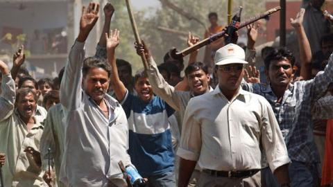A mob of Hindus wielding swords and sticks back off after Indian Rapid Reaction Force officers stopped them from attacking a small group of Muslims March 1, 2002 in Ahmadabad, India. (Ami Vitale/Getty Images)