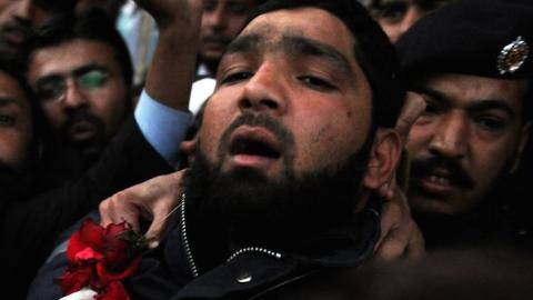 Arrested Pakistani bodyguard Malik Mumtaz Hussain Qadri wearing a garland leaves the court in Islamabad on January 5, 2011 a day after the assassination of the governor of Punjab province Salman Taseer. (AAMIR QURESHI/AFP/Getty Images)