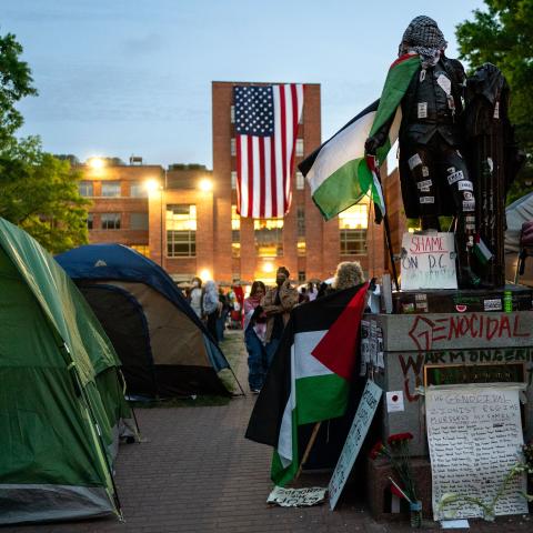 An American flag hangs from the roof of Lisner Hall of the George Washington University Law School as people walk around an encampment at University Yard on May 3, 2024 in Washington, DC. Pro-Palestinian encampments have sprung up at college campuses around the country with some demonstrators calling for schools to divest from Israeli interests amid the ongoing war in Gaza. (Photo by Kent Nishimura/Getty Images)