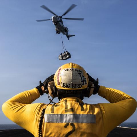 A U.S. Sailor directs a Eurocopter AS-332 Super Puma on the flight deck of Nimitz-class aircraft carrier USS Abraham Lincoln (CVN 72) during a replenishment-at-sea with fleet replenishment oiler USNS Henry J. Kaiser (T-AO-187), Aug. 16, 2026. Abraham Lincoln is deployed to the U.S. 5th Fleet area of operations to support maritime security and stability in the Middle East. (U.S. Navy photo)