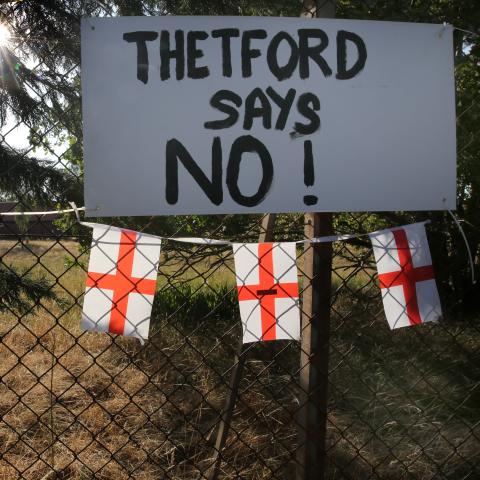 A sign attached to the camp fence says, “Thetford Says No!” at RAF Barnham on August 7, 2026, in Thetford, UK. A protest camp has been set up by locals who oppose the use of RAF Barnham as a site for 1,250 asylum seekers. (Getty Images)