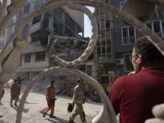 Iranian workers walk past a destroyed residential building due to Israeli attacks in Tehran, Iran, on June 13, 2025. (Photo by Morteza Nikoubazl/NurPhoto via Getty Images)