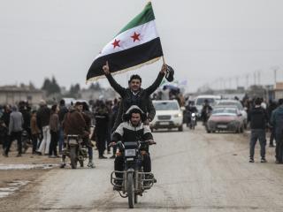 Men riding a motorbike wave a Syrian flag as Syrian government forces enter the Kurdish-majority city of Qamishli on February 3, 2026. (Getty Images)