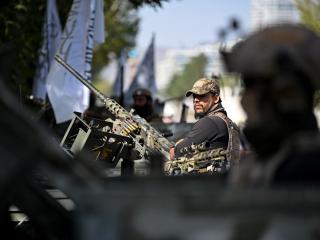 Taliban security personnel stand guard atop armored Humvees along a road in the Green Zone area in Kabul on August 12, 2026. (Getty Images)