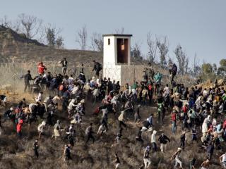 Migrants storm a barbed-wire fence as they attempt to cross the land border with Spain's African enclave of Ceuta near Fnideq in northern Morocco on September 15, 2024. (Photo by AFP) (Photo by -/AFP via Getty Images)