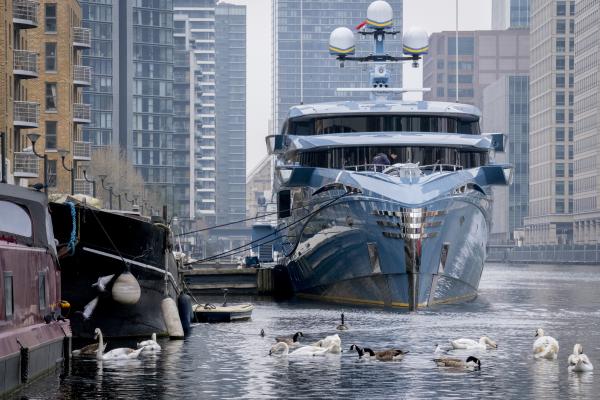 A local boat resident feeds local birdlife alongside the 58m (192ft) £38m super-yacht 'Phi' which remains seized at 'Dollar Bay' in London Docklands, impounded by the UK's National Crime Agency (NCA) because of sanctions against Putin associates during the Russian invasion of Ukraine, on 30th March 2022, in London, England. The Phi has its own swimming pool and infinite wine cellar, according to its Dutch builders. Its ownership is uncertain but it is believed to be owned by a Russian businessman with links