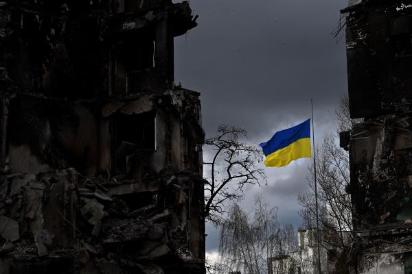 The Ukrainian flag flutters between buildings destroyed in bombardment in Borodianka, Ukraine, on April 17, 2022. (Sergei Supinsky/AFP via Getty Images)