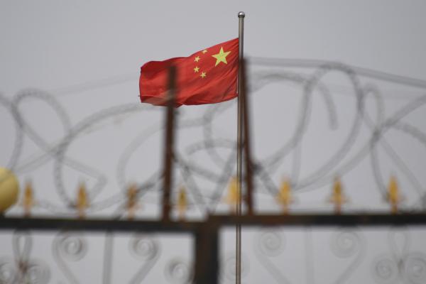 The Chinese flag behind razor wire at a housing compound in Yangisar in China's western Xinjiang region. (Greg Baker/AFP via Getty Images)