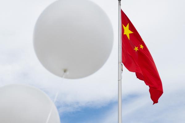 Two white balloons float near the Chinese flag during a demonstration outside the Chinese Embassy in Washington, DC, on February 15, 2023. (Photo by Saul Loeb/AFP via Getty Images)