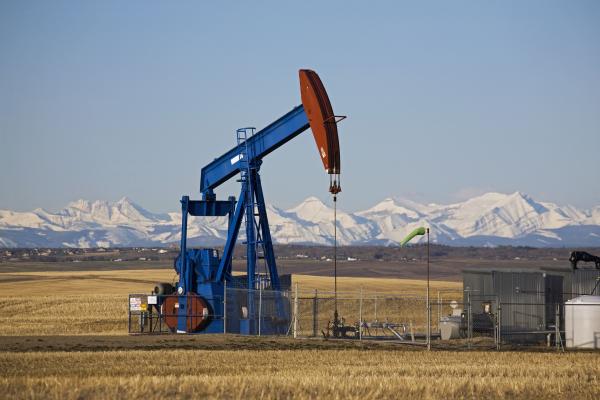 Pumpjack in a field with snow covered mountains in Alberta, Canada. (Michael Interisano/Universal Images Group via Getty Images)