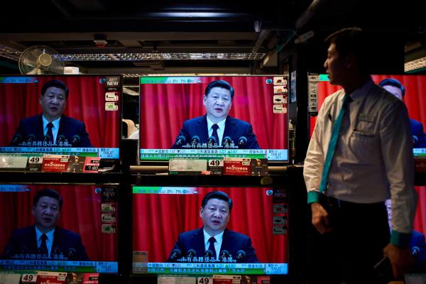 An electronics shop employee in Hong Kong on October 18, 2017, looks at television sets showing a news report on China's President Xi Jinping's speech at the opening session of the Chinese Communist Party's five-yearly Congress. (Anthony Wallace/AFP via Getty Images)