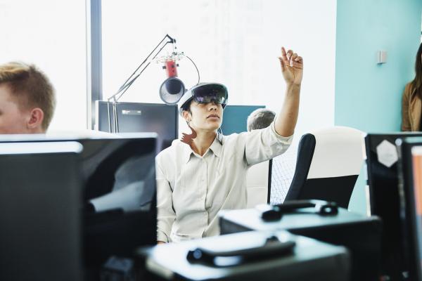 Female engineer testing program on augmented reality headset in computer lab 