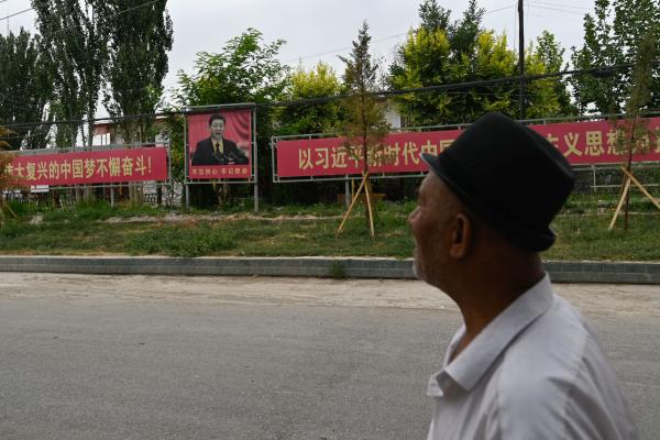 A man passes a portrait of Chinese President Xi Jinping accompanied by a propaganda slogan in Xinjiang, China, on July 16, 2023. (Photo by Pedro Pardo/AFP via Getty Images)