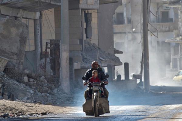 A Syrian man and a child ride a motorcycle in the Islamic State (IS) group's former Syrian capital of Raqa in northern Syria.