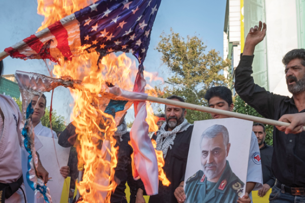 Iranian protesters burn US and Israeli flags next to a portrait of Major General Qasem Soleimani during an anti-Israel protest in downtown Tehran on August 9, 2022. (Morteza Nikoubazl/NurPhoto via Getty Images)