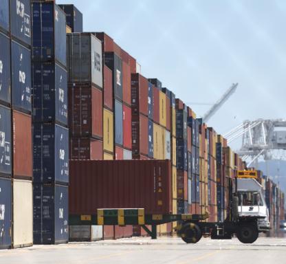 A truck drives by stacks of shipping containers at the Port of Oakland on May 20, 2022 in Oakland, California.