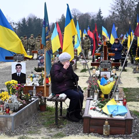 An elderly woman grieves next to the grave of a Ukrainian soldier during Ukraine's Army Day in Lviv, Ukraine, on December 6, 2022. (Yuriy Dyachyshyn/AFP via Getty Images)