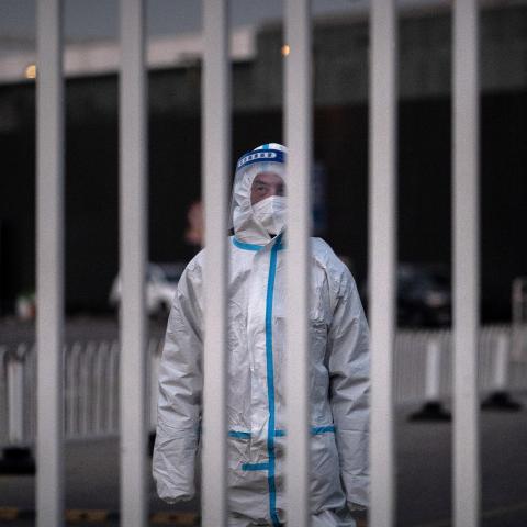 An epidemic control worker guards the gate of a government quarantine facility on December 7, 2022, in Beijing, China. (Kevin Frayer/Getty Images)