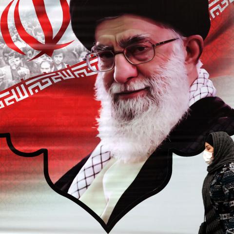 An Iranian woman walks past a mural showing Iran's Supreme Leader Ayatollah Ali Khamenei in the capital Tehran on March 9, 2022. (Photo by ATTA KENARE / AFP) (Photo by ATTA KENARE/AFP via Getty Images)