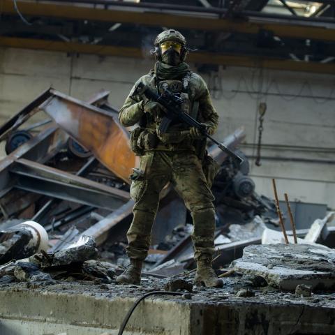 A Ukrainian soldier with an assault rifle stands amid wreckage as debris lie in the garage at a trolleybus depot on January 27, 2023, in Bakhmut, Ukraine. (Yan Dobronosov/Global Images Ukraine via Getty Images)