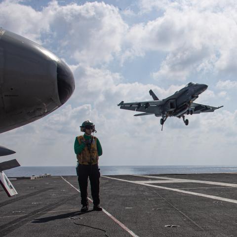 Aviation Boatswain's Mate observes an F/A-18E Super Hornet attached to the "Tomcatters" of Strike Fighter Squadron landing on the flight deck of the world’s largest aircraft carrier USS Gerald R. Ford in the Eastern Mediterranean Sea on October 13, 2023. (Jacob Mattingly via DVIDS)