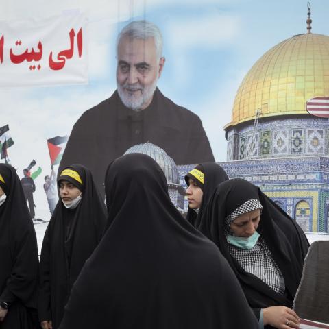 A veiled Iranian woman holds an effigy of US President Joe Biden while standing in front of a portrait of the former commander of Iran’s Islamic Revolutionary Guard Corps (IRGC) Quds Force, General Qasem Soleimani, and an image of al-Aqsa mosque during a rally commemorating the International Quds Day in downtown Tehran on April 29, 2022. (Photo by Morteza Nikoubazl/NurPhoto via Getty Images)