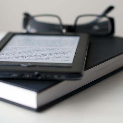 E-Reader and book with reading glasses.