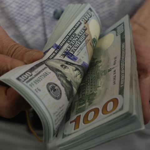 A teller flicks through a bundle of US dollar bills at an exchange office in Ankara on July 20, 2023. (Adem Altan/AFP via Getty Images)