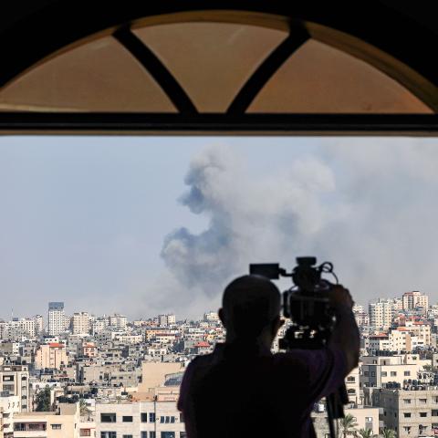 An AFPTV cameraman films while smoke plumes billow during Israeli air strikes in Gaza City on October 12, 2023. (Photo by MOHAMMED ABED / AFP) (Photo by Mohammed Abed/AFP via Getty Images)